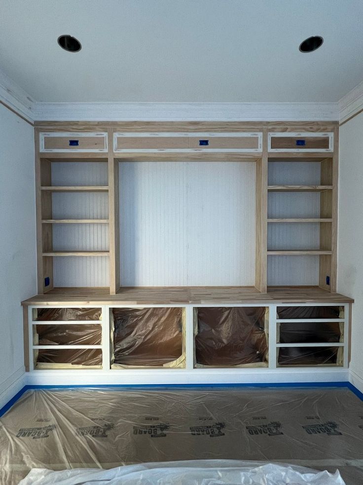 an empty room with some shelves in the middle and plastic on the floor next to it