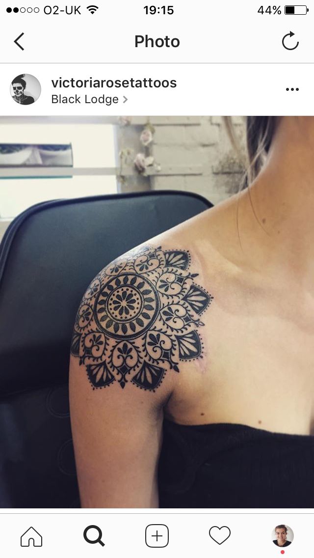 the back of a woman's shoulder with an intricate tattoo design on her left arm