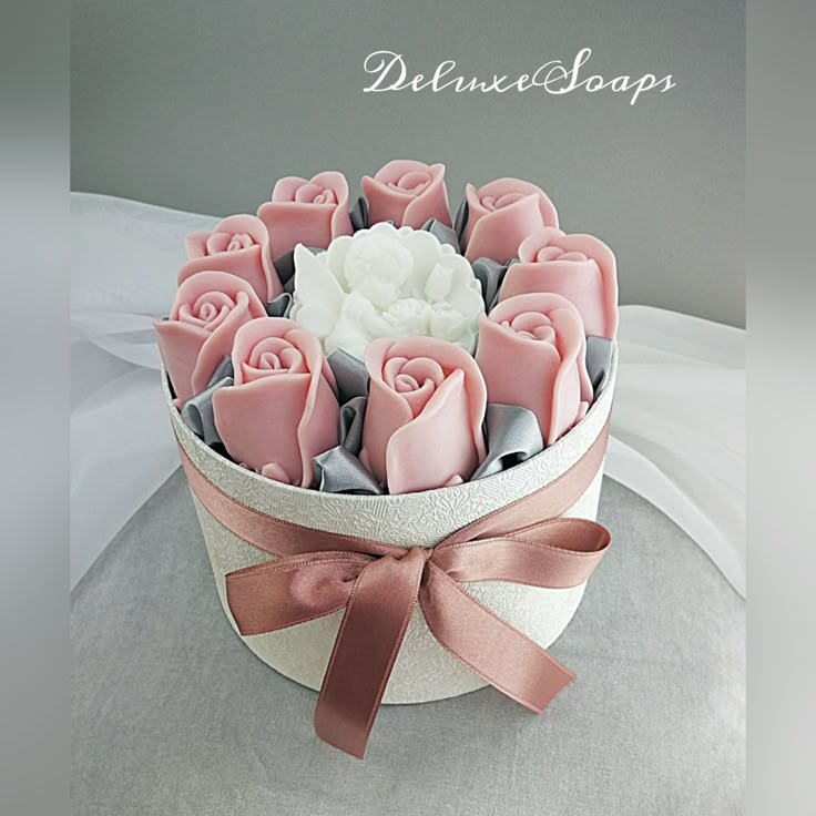 a bouquet of pink and white roses in a paper box with ribbon on the top