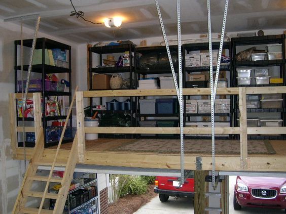 a car is parked in front of a garage with shelves and ladders on the wall