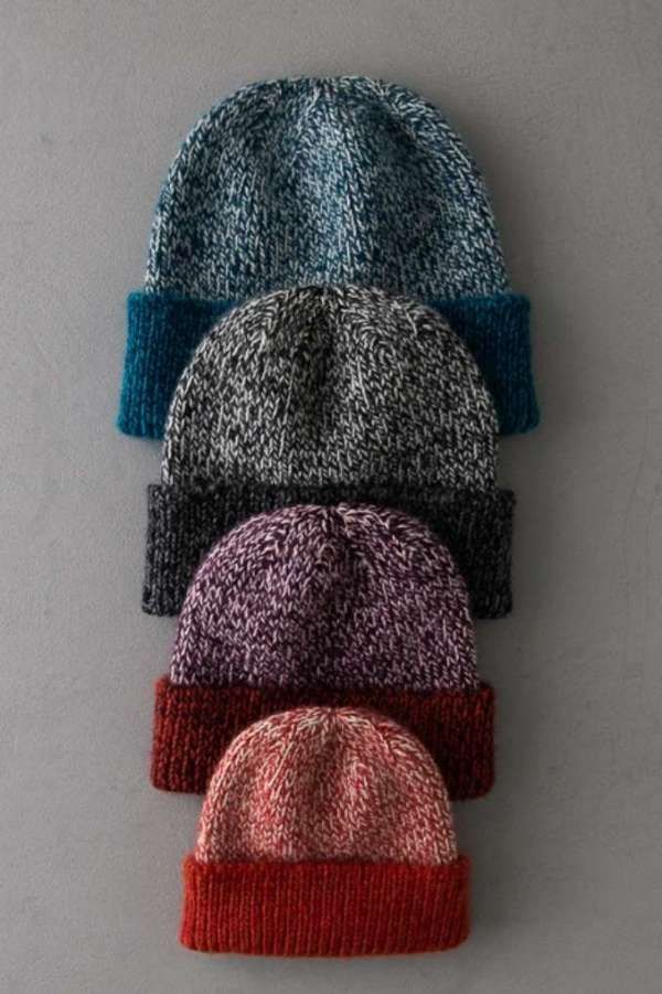 three knitted hats sitting on top of a white table next to each other, all different colors