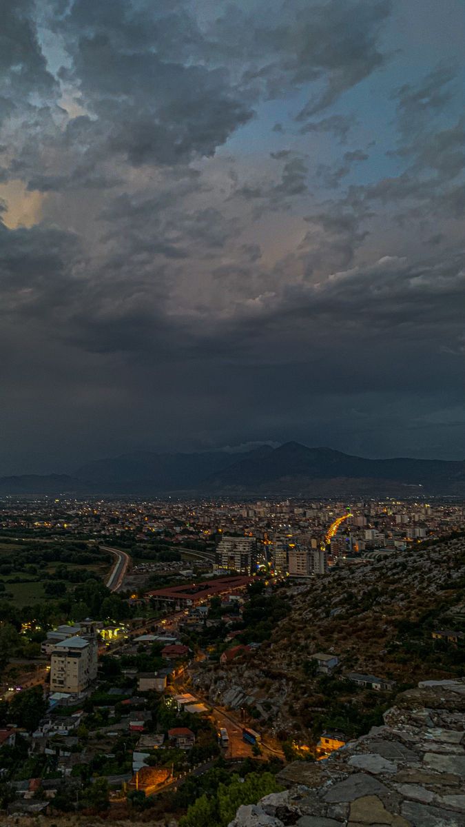 the city is lit up at night with clouds in the sky