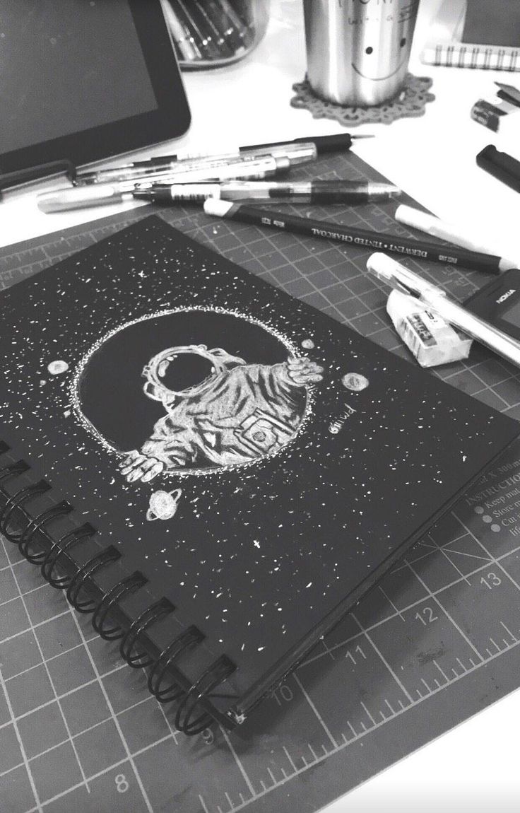 a black and white photo of a notebook with a tiger on it, surrounded by pencils