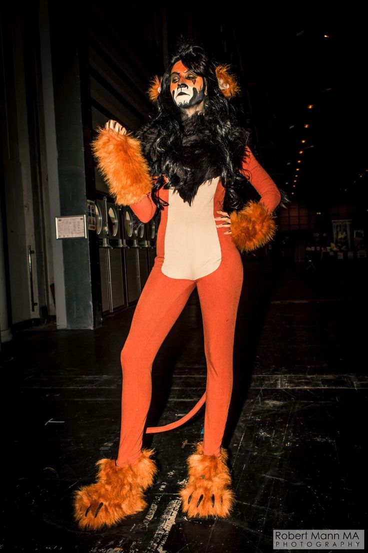 a woman dressed in an orange and white cat costume standing next to a building at night