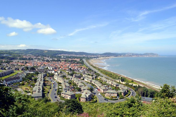 an aerial view of a town by the ocean with houses on each side and trees in the foreground