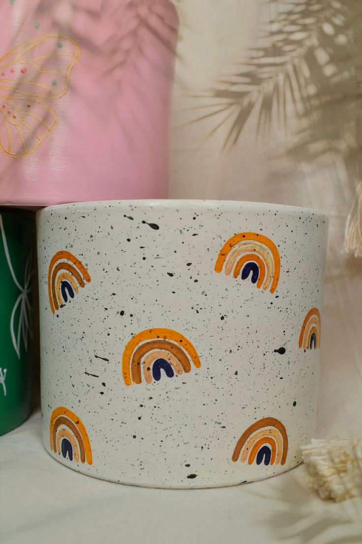 two mugs sitting next to each other on a white surface with palm leaves in the background