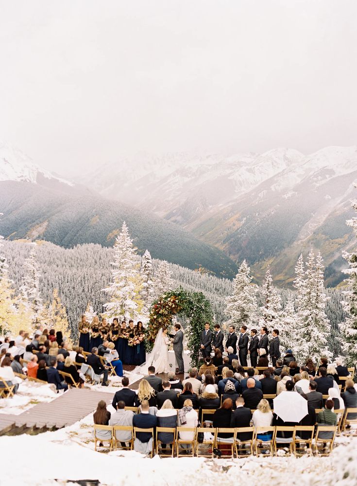 a wedding ceremony in the mountains with snow on the ground and people sitting at chairs