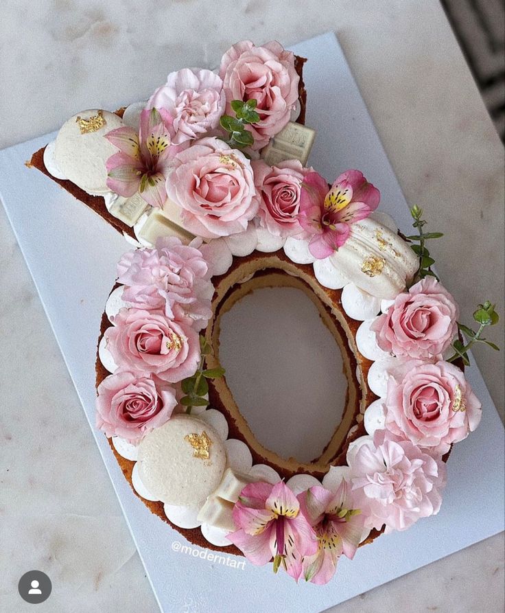 a cake decorated with pink flowers on top of a white countertop next to a knife