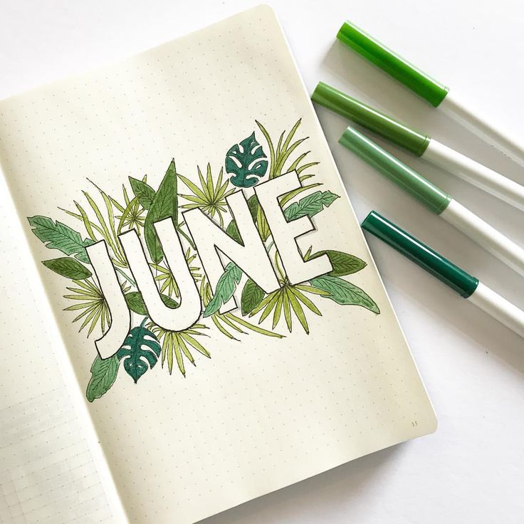 an open notebook with the word june written in green leaves and surrounded by four markers