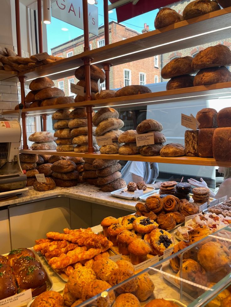 a bakery filled with lots of different types of breads and muffins on display