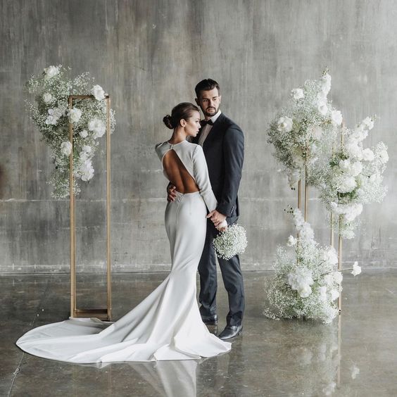 a man and woman standing next to each other in front of white flowers on display