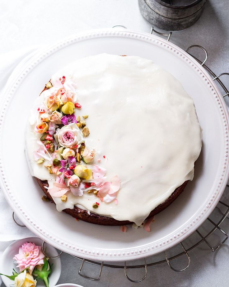 a white plate topped with a cake covered in frosting and flowered toppings