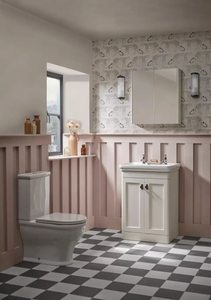 a white toilet sitting next to a sink in a bathroom with pink walls and black and white checkered floor