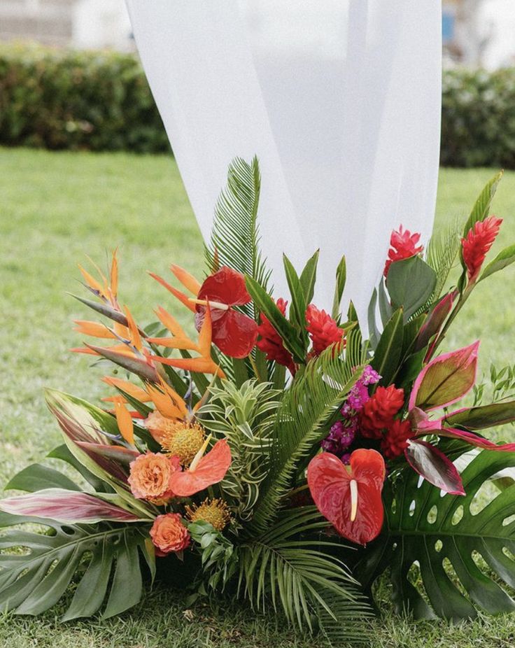 an arrangement of tropical flowers and greenery on the ground at a wedding ceremony in hawaii