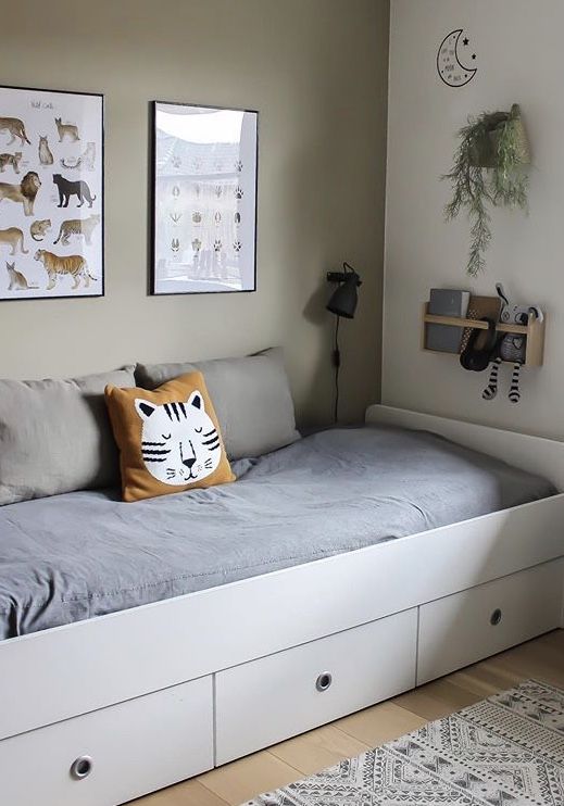 a white daybed with drawers underneath it in a room filled with pictures and rugs