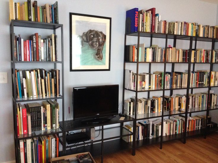 a living room with bookshelves full of books and a flat screen tv on the wall