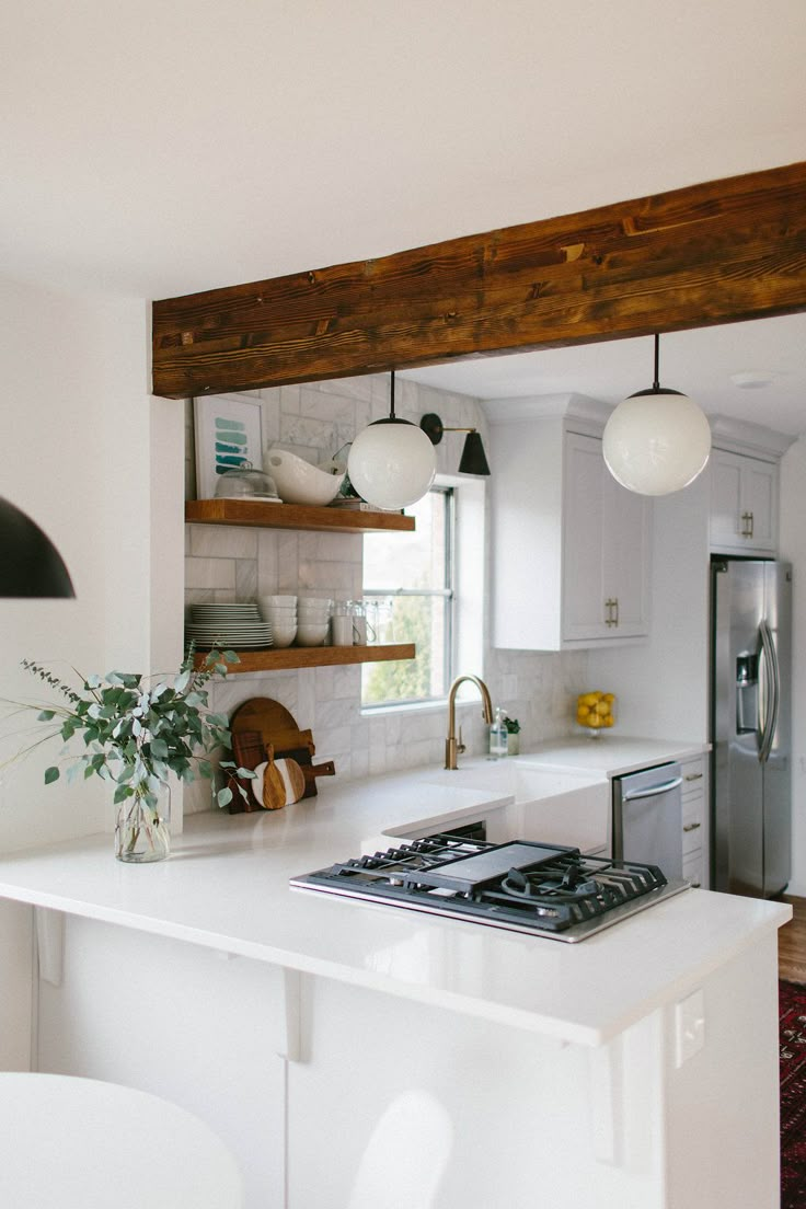 a kitchen with white counter tops and wooden beams