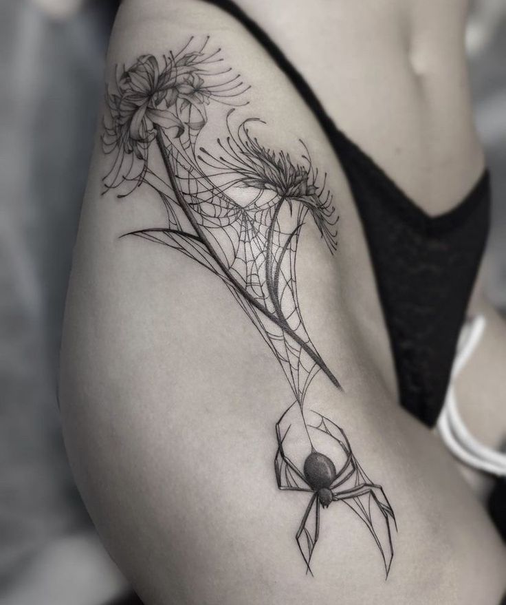 a woman's thigh with a spider and flowers tattoo on her lower back side