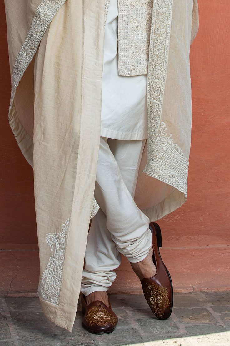 Beige achkan embroidered all-over with resham beadwork and dabka. Paired with tussar silk kurta and cotton lycra pant.
Component: 3
Pattern: Embroidered
Type Of Work: Dabka, Resham, Bead
Neckline: Mandarin
Sleeve Type: Full
Fabric: Achkan: Moonga Silk, Kurta: Monga Tussar
Color: Beige
Other Details: 
Dabka and resham work
Note: Stole, safa, neckpieces and kalangi worn by the model is not for sale
Occasion: Wedding,Groom - Aza Fashions Ivory Sherwani, Dabka Embroidery, Garden Pattern, Geometric Embroidery, Silk Kurta, Beaded Neckline, Band Collar, Churidar, Embroidered Silk