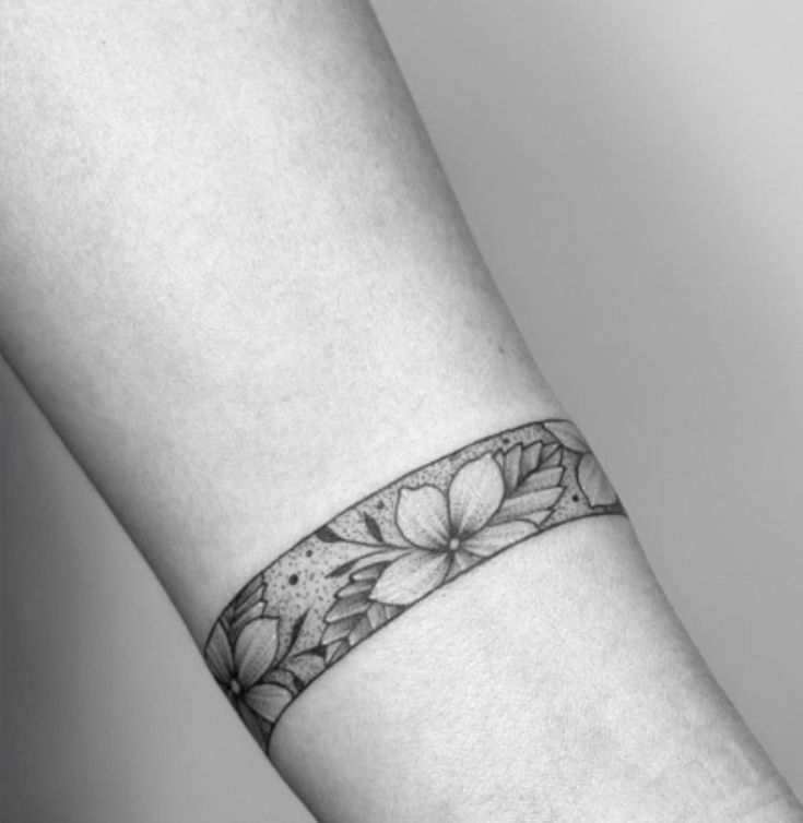 a black and white photo of a woman's arm with a flower tattoo on it