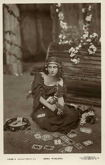 an old black and white photo of a woman sitting on the ground with playing cards