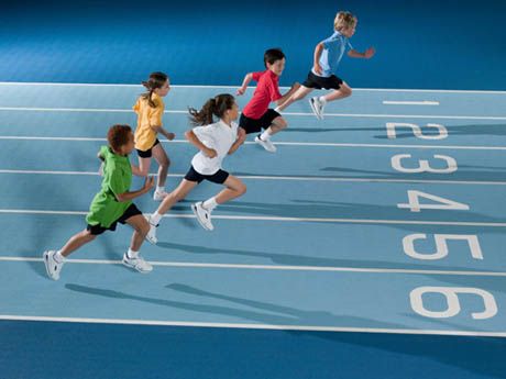 four children running on a blue tennis court