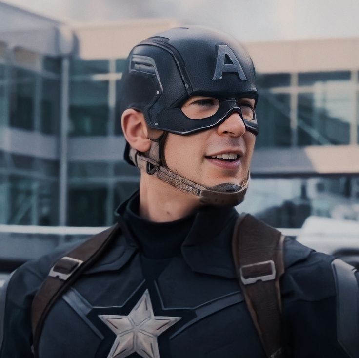 a man dressed as captain america standing in front of a building with his helmet on