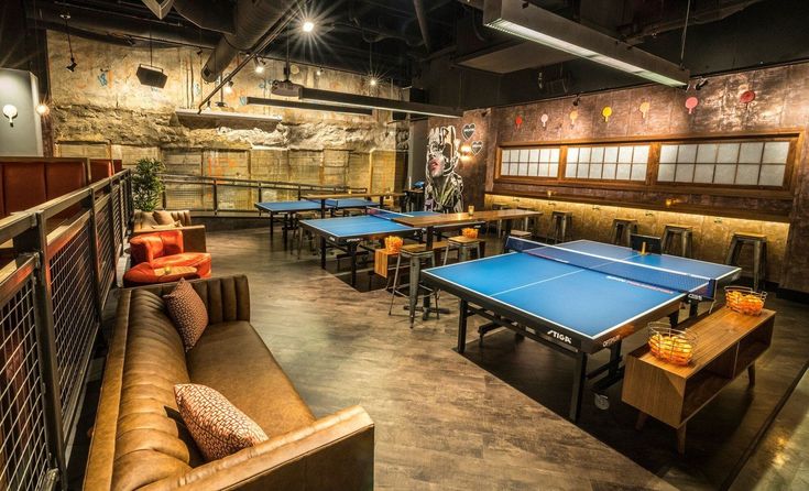 an indoor ping pong room with tables and couches