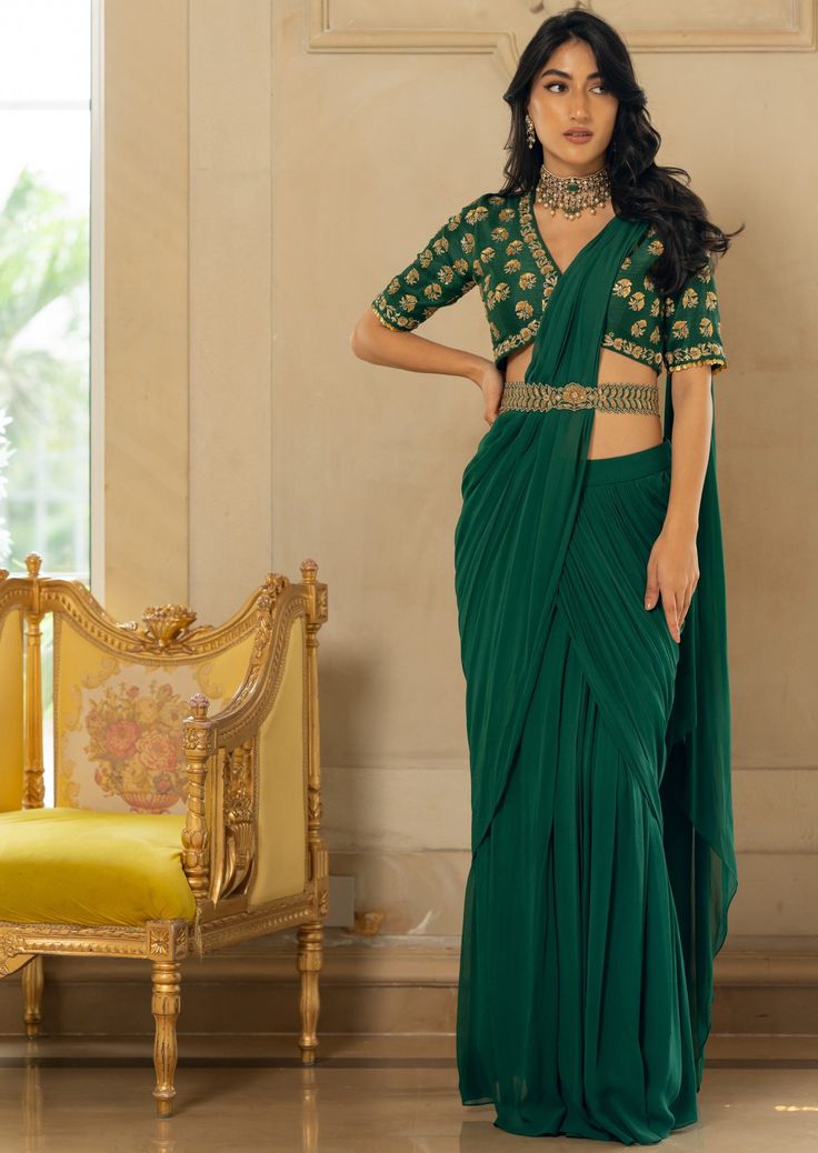 Featuring an emerald green pre-draped sari set paired with raw silk antique motif hand embroidered blouse and our signature belt. Green Pre-draped Saree For Reception, Green Draped Silk Sets, Green Draped Lehenga With Cutdana, Green Draped Saree For Wedding, Green Bollywood Draped Set, Elegant Draped Green Lehenga, Elegant Green Draped Blouse Piece, Festive Green Pre-draped Saree, Green Draped Sets With Zari Work