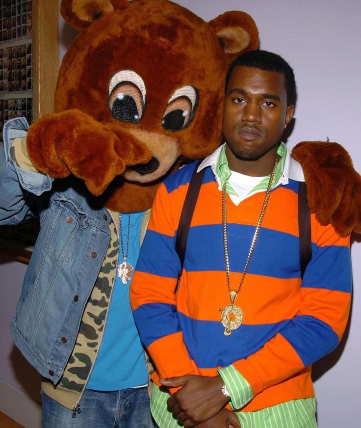 two men standing next to each other in front of a large stuffed animal bear head