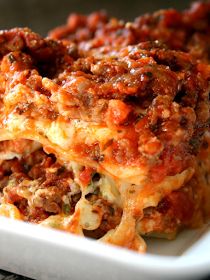 lasagna casserole on a white plate with meat toppings and cheese