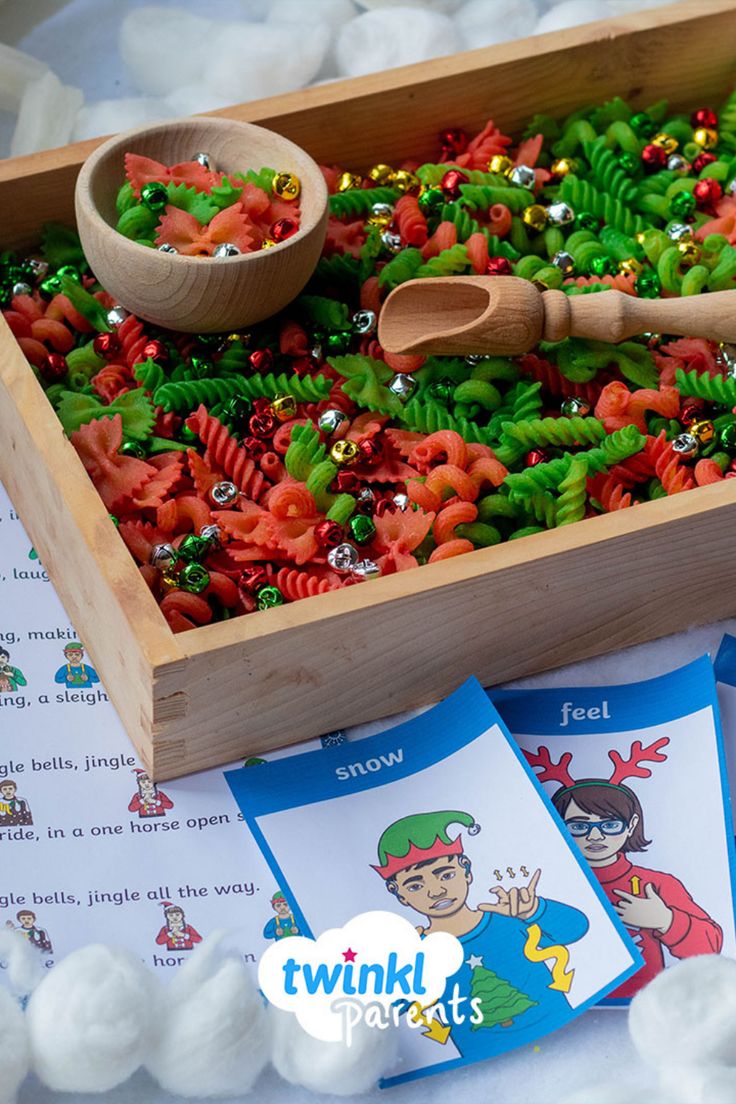 a wooden box filled with lots of different colored candies next to two matching cards