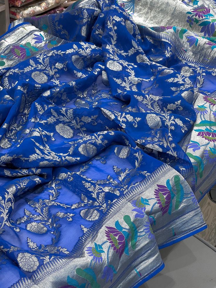 Expertly crafted in the traditional Maharashtrian style, this Blue Georgette Paithani Saree is a stunning and elegant choice for any occasion. Made with sliver zari it boasts a unique and luxurious look. Perfect for those who appreciate the art and beauty of Indian fashion. Elegant Royal Blue Saree For Wedding, Silver Chanderi Traditional Wear For Eid, Elegant Silver Traditional Wear With Dupatta, Elegant Silver Festive Traditional Wear, Royal Blue Banarasi Silk Dupatta For Puja, Traditional Blue Dupatta With Patterns, Royal Blue Banarasi Silk Traditional Wear For Puja, Unstitched Silver Dupatta With Zari Work, Silver Dupatta With Zari Work