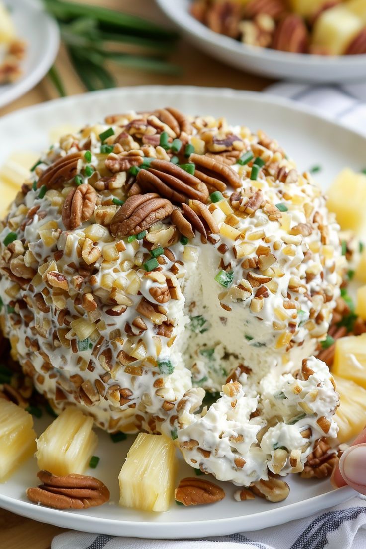 a white plate topped with pineapples and whipped cream covered in pecans next to other plates