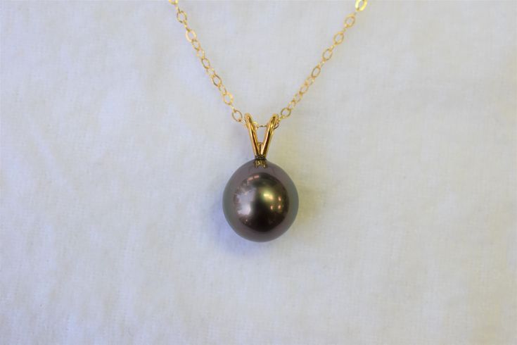 PLEASE CHECK OUR SHOP ANNOUNCEMENTS FOR PROCESSING TIMES :) The size of the Tahitian black pearl is approximately 10x10.5mm. The pearl is slightly teardrop shape. It has slightly dark gray overtones and high luster and minor blemishes. The rabbit ear finding and the chain is in 14K yellow gold. The total length of the pendant is approximately 5/8 inches long. Please visit our shop policies for more details! We only use real pearls in all of our jewerly. For more information, Like us on Facebook, Tahitian Pearl Necklace With Round Pendant, Black Tahitian Pearl Round Bead Necklaces, Black Tahitian Pearl Pendant Necklaces, Black Pearl Drop Round Jewelry, Black Pearl Round Pendant Jewelry, Black Pearl Pendant, Freshwater Pearl Ring, Tahitian Black Pearls, Real Pearls