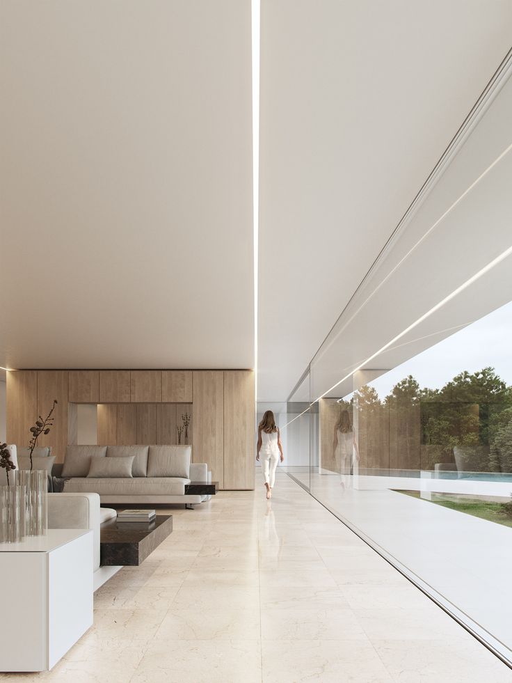 a woman walking through a large white living room