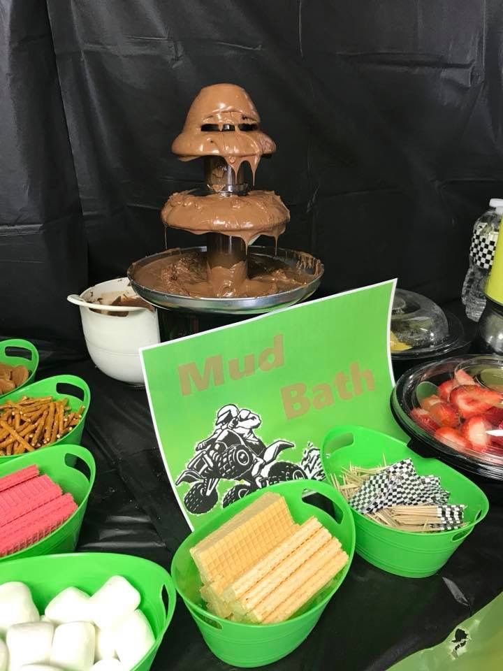 a table topped with green buckets filled with food next to a black wall covered in writing