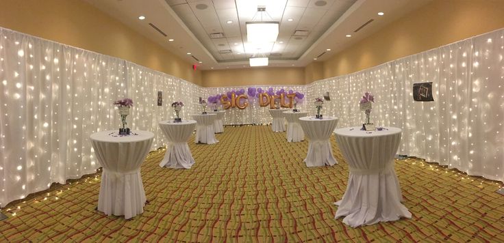 the banquet room is decorated with white tablecloths and purple flower centerpieces