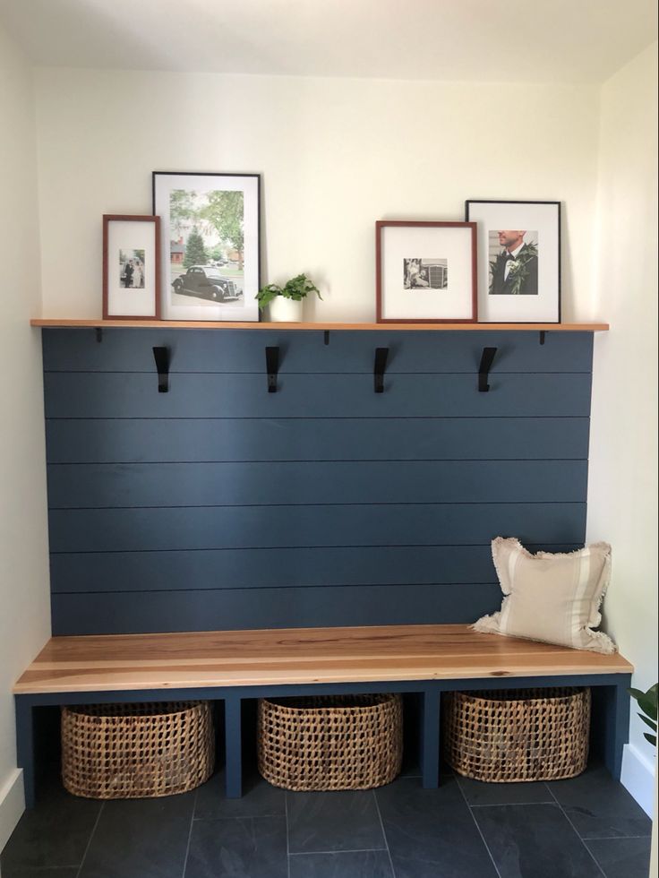 a bench with baskets underneath it and pictures on the wall