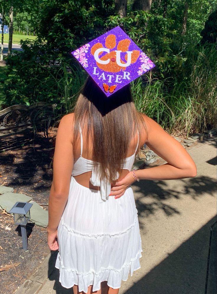 a woman wearing a purple and orange graduation cap with the word u s later on it