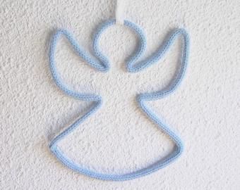 a crocheted angel ornament hanging from the ceiling on a white wall