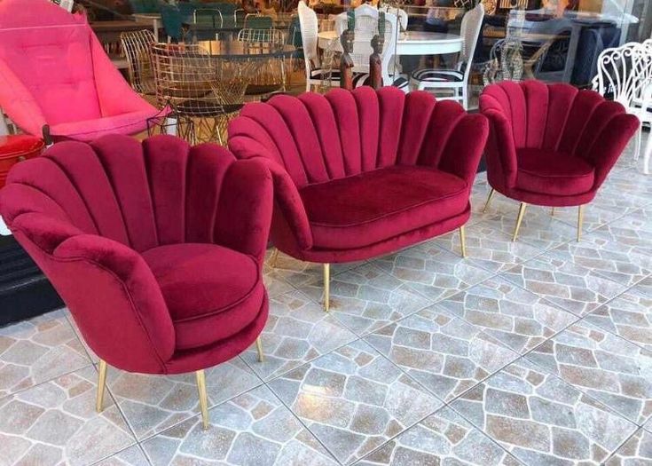 three red chairs sitting next to each other on a stone floor in front of a store