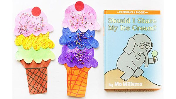 two ice cream cones are next to an old children's book, and one is made out of paper