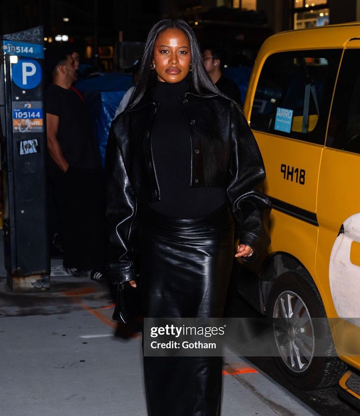 a woman is seen walking down the street at night wearing a black leather skirt and high heels