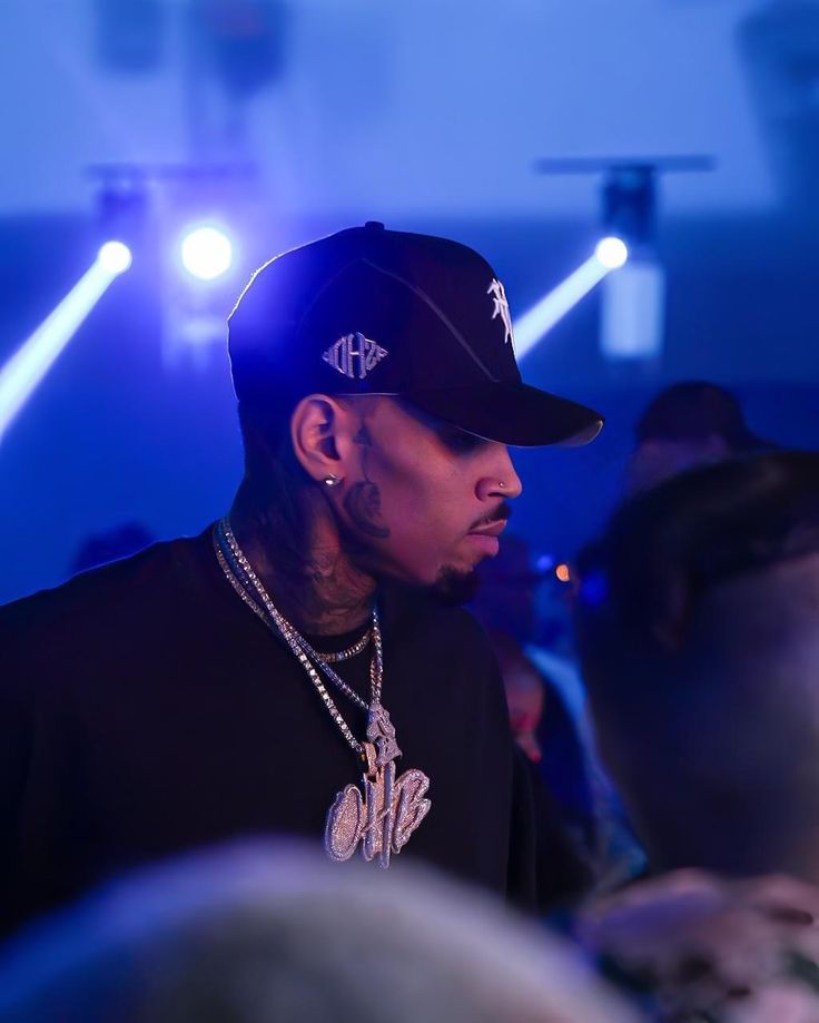 a man wearing a black hat and some lights in front of him at a concert