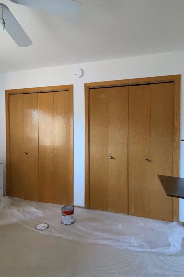 an empty room with two wooden doors and some white paint on the floor in front of them