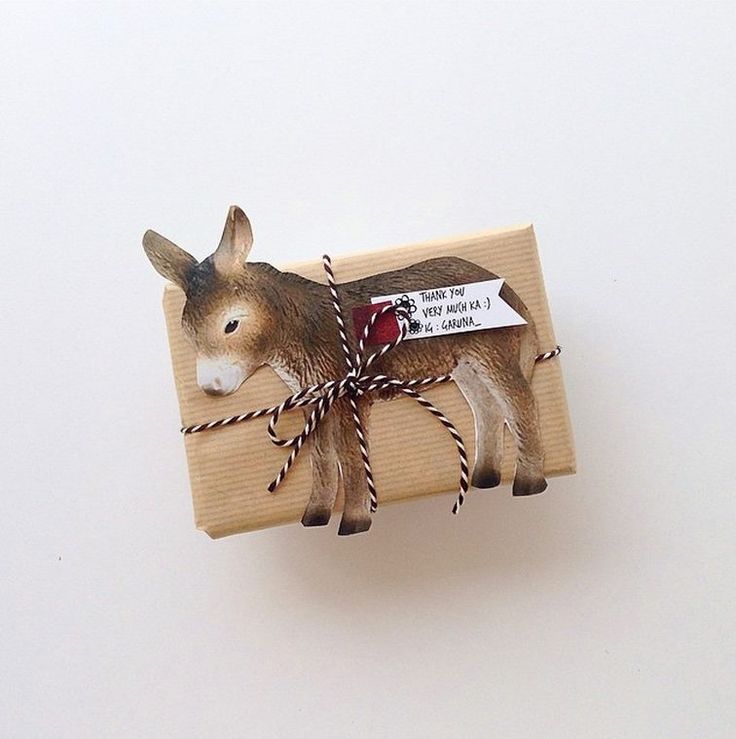 a small donkey wrapped in twine and tied to a piece of wood with a tag on it