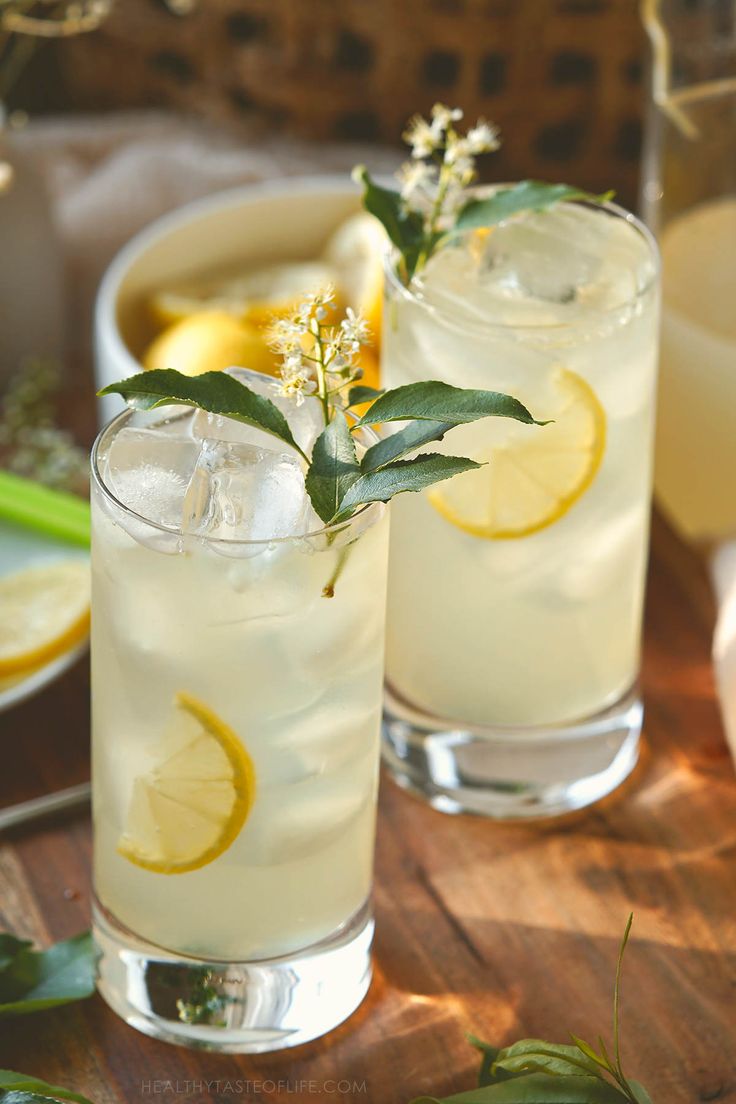 two glasses filled with lemonade sitting on top of a wooden table