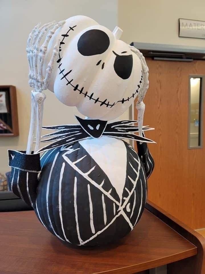 a pumpkin decorated like a skeleton sitting on top of a table