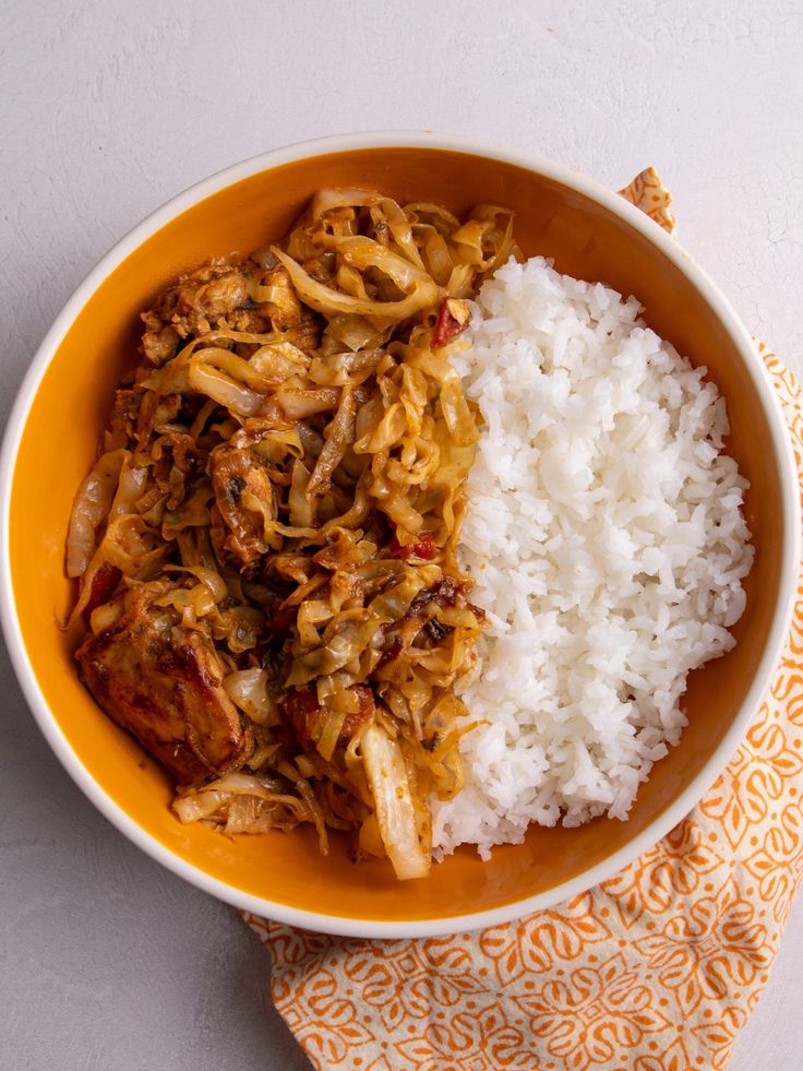 a bowl filled with rice and meat next to a napkin on top of a table